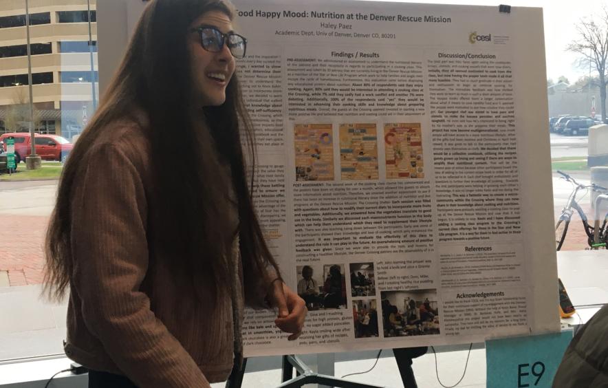 girl with glasses and long hair presenting a research poster